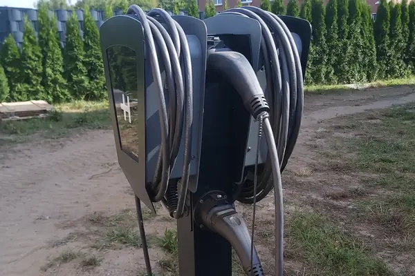 Ladestation für Elektroautos mit zwei Wallboxen, aufgewickelten Ladekabeln und angeschlossenen Steckern im Außenbereich.