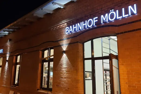 Beleuchtung der Backsteinfassade am Bahnhof Mölln mit illuminiertem Schriftzug und angestrahltem Eingangsbereich.