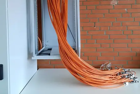 Netzwerktechnik im Aufbau mit gebündelten Datenkabeln, vorbereiteten RJ45-Anschlüssen und offenem Netzwerkschrank.