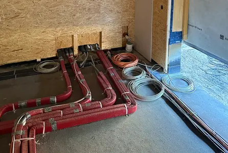 Elektroinstallation im Rohbau mit verlegten Schutzrohren, Kabelschleifen und vorbereiteten Leitungswegen im Fußbodenbereich.