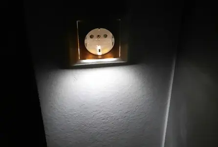 Dezente Beleuchtung unter einer Steckdose erzeugt Orientierungslicht und eine ruhige Lichtwirkung an der Wand.
