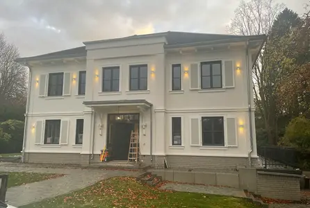 Warme Beleuchtung setzt die Fassade einer Villa mit Eingangsbereich und Fensterachsen dezent in Szene.